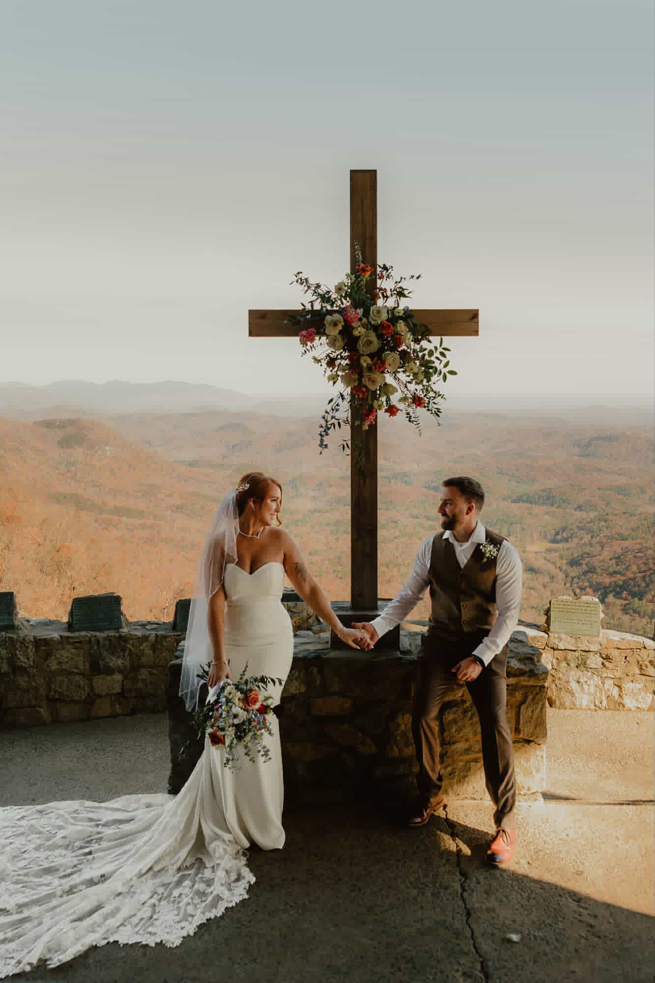 Couple at floral cross installation with mountain backdrop