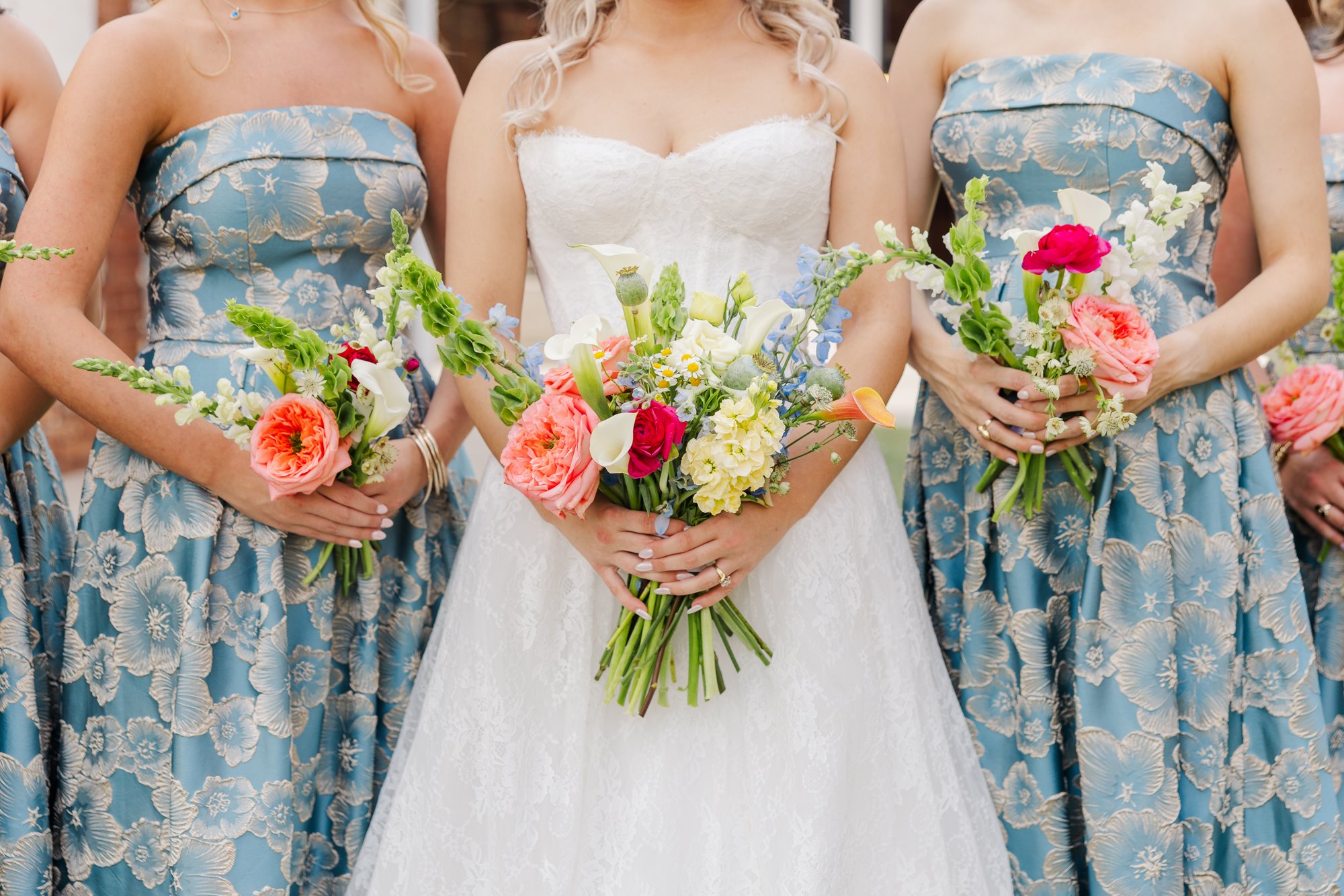 Bride and bridesmaids in blue floral dresses holding bouquets