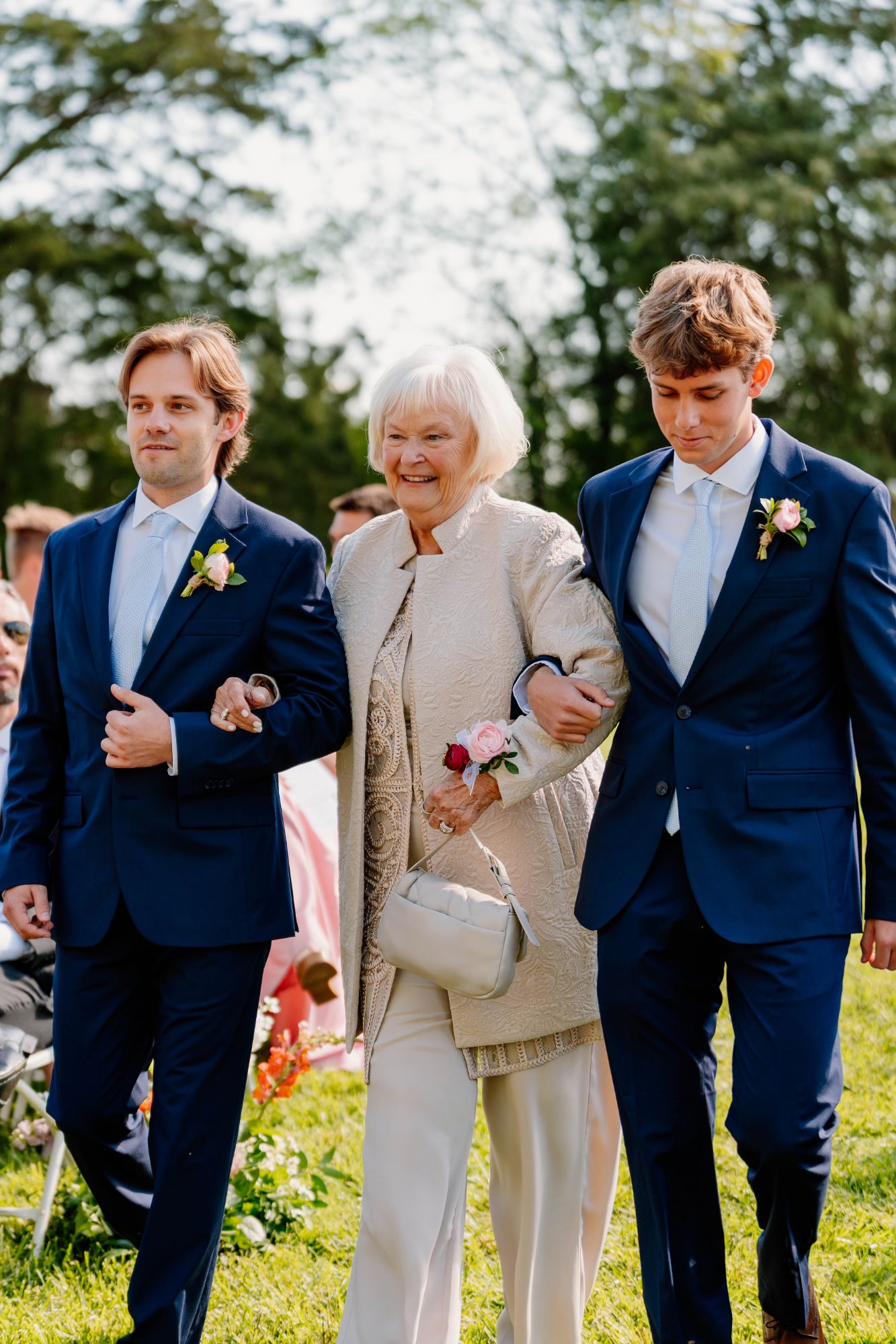 Grandmother being escorted down the aisle wearing a corsage